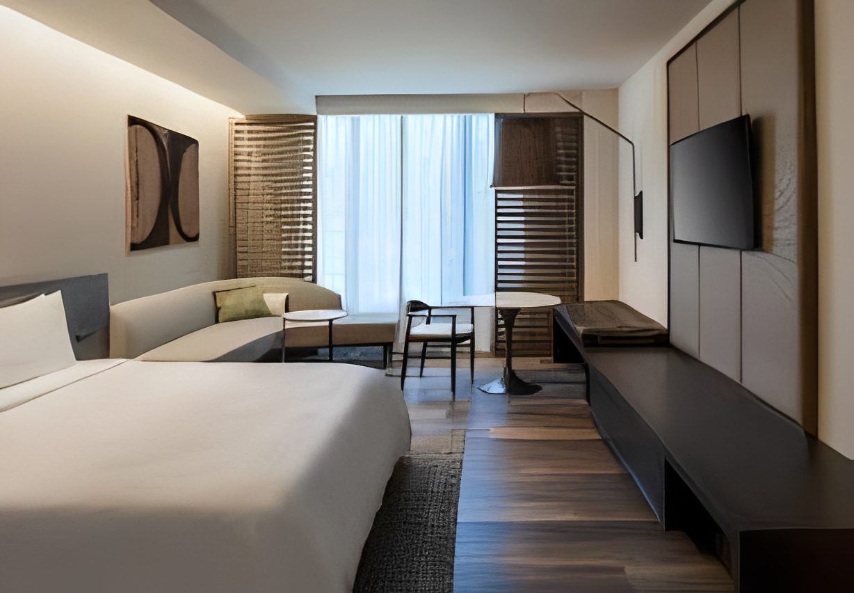 Modern hotel room with bed and seating area.